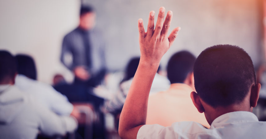 Foto van een jongen die zijn hand opsteekt in de klas