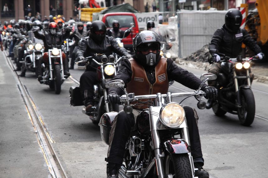 Een groep motorrijders in clubkleding rijdt over straat