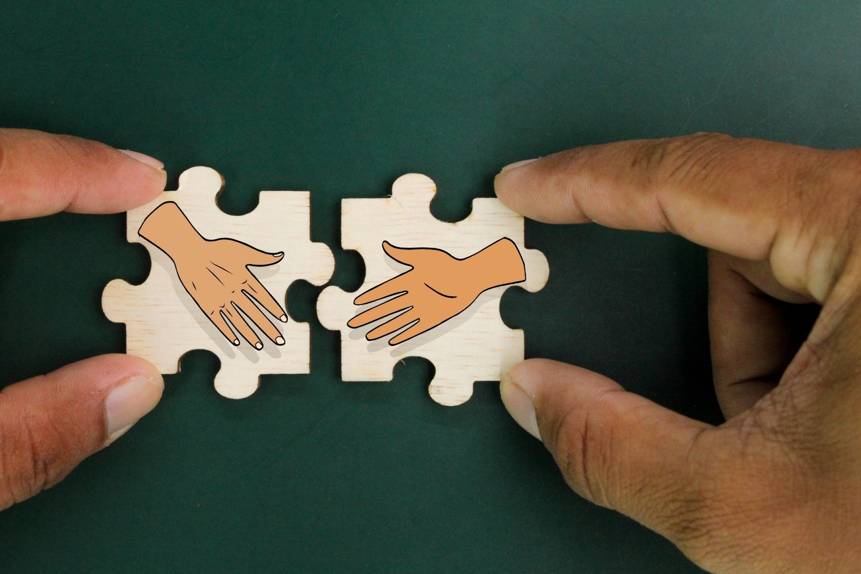 Twee puzzelstukjes met handen erop, die in elkaar worden geschoven.